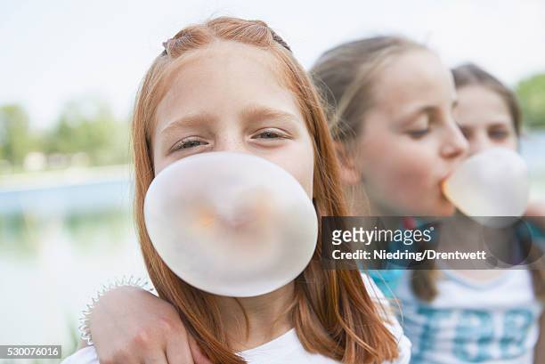 girls blowing chewing gum bubbles, bavaria, germany - bubble gum kid stock pictures, royalty-free photos & images