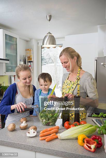 mother and children preparing salad in kitchen, smiling - vinegar stockfoto's en -beelden