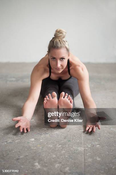 mid adult woman practicing seated forward bend pose in yoga studio, munich, bavaria, germany - female soles stockfoto's en -beelden