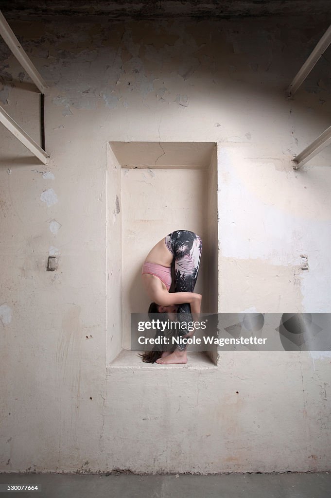 Mid adult woman practicing uttanasana pose in alcove, Munich, Bavaria, Germany