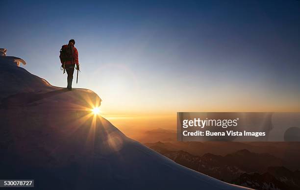 climber on a snowy range at sunset - motivatie stockfoto's en -beelden