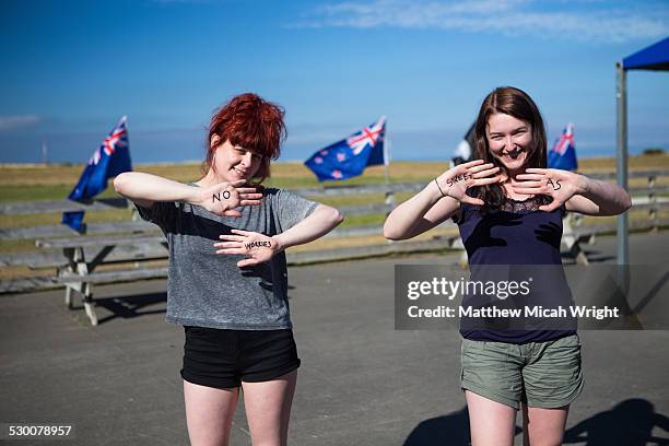 Girls write traditional Kiwi greetings on hands.