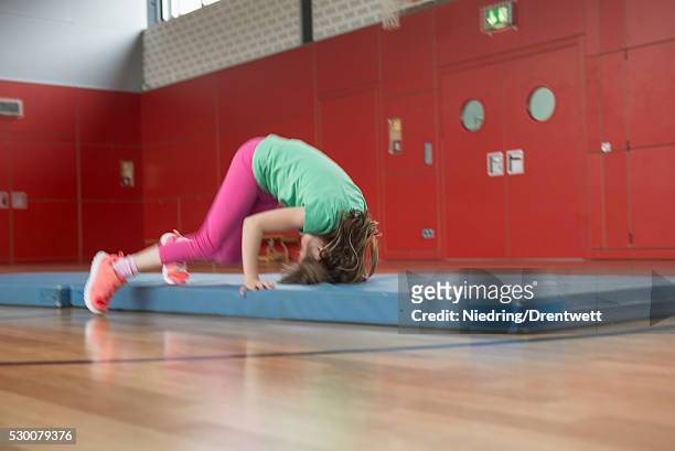girl doing somersault on exercise mat in sports hall, munich, bavaria, germany - school gymnastics stock pictures, royalty-free photos & images