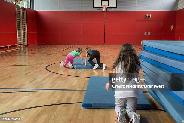 girls arranging the sports mats in basketball court, munich, bavaria, germany - school gymnastics stock-fotos und bilder