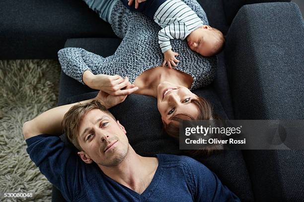 family with baby boy relaxing on couch - high angle view home stock pictures, royalty-free photos & images