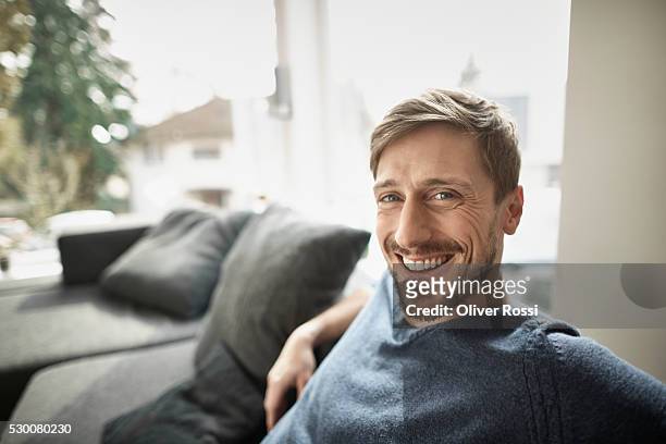 portrait of smiling man in living room - content photos et images de collection