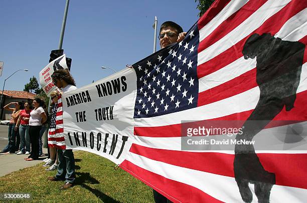 Fans show support for accused child molester Michael Jackson with an American flag bearing a likeness of the singer dancing as they wait for...