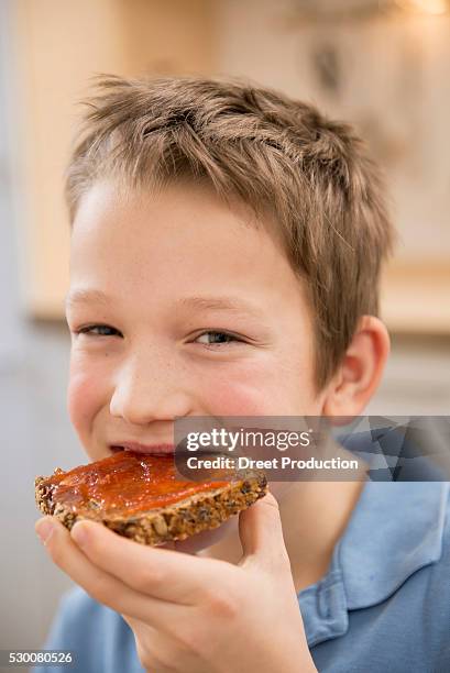 portrait of smiling boy eating bread with jam - croquant photos et images de collection