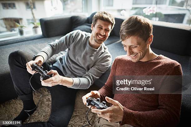two friends in living room playing video game - games console stock-fotos und bilder