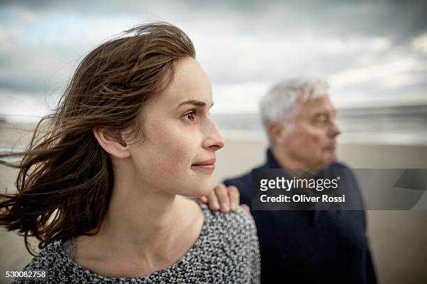 senior man with adult daughter on the beach - senior adult stock-fotos und bilder