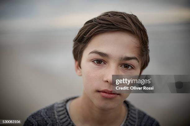 portrait of serious boy on the beach - serious teenager boy stock-fotos und bilder