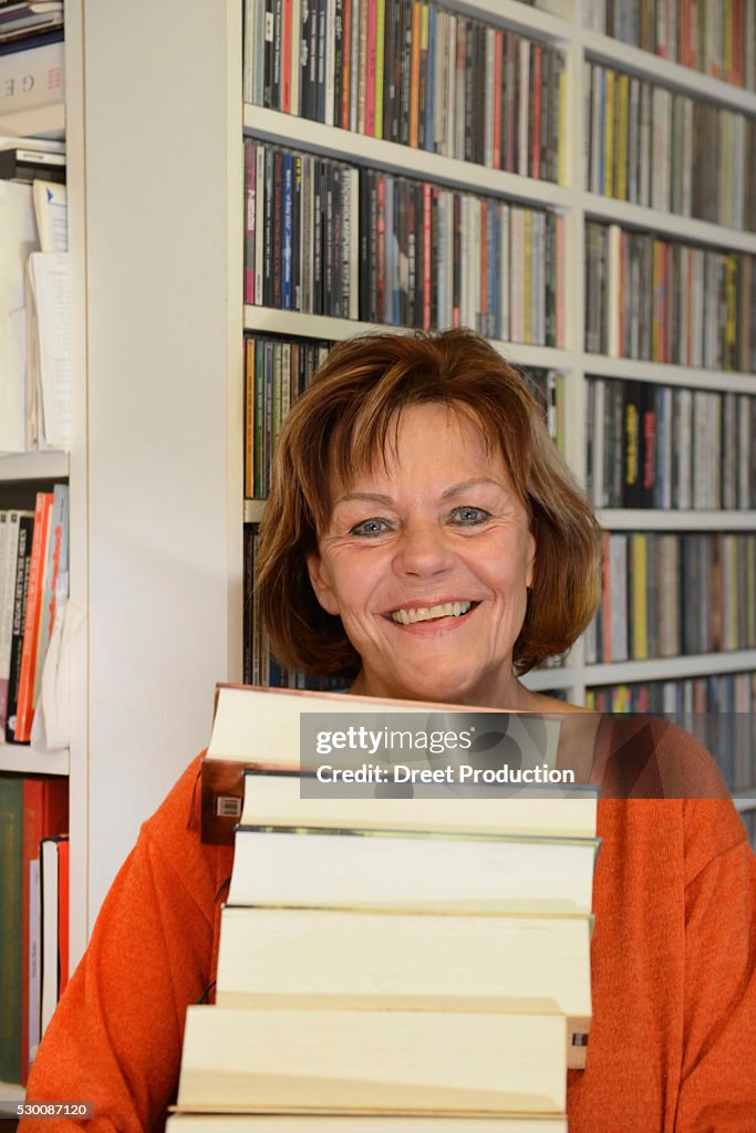 Senior woman with stack of books, smiling, portrait