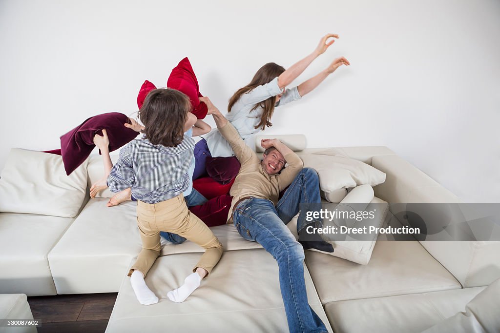 Family doing pillow fight on couch