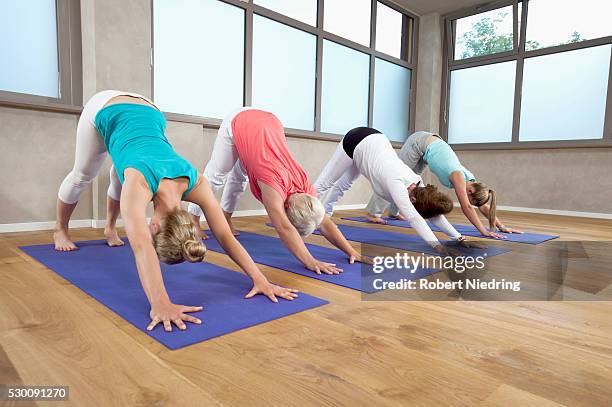 four women fitness studio yoga stretching exercise - downward facing dog position stock pictures, royalty-free photos & images