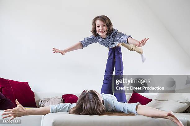 mother balancing her daughter on her feet - 飛行機のまね ストックフォトと画像