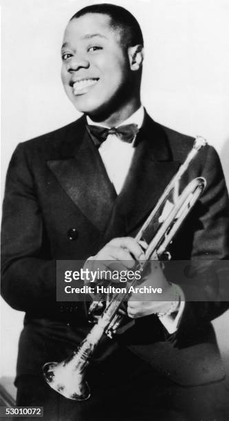 Portrait of jazz musician and actor Louis Armstrong posing with his trumpet, late 1920s.
