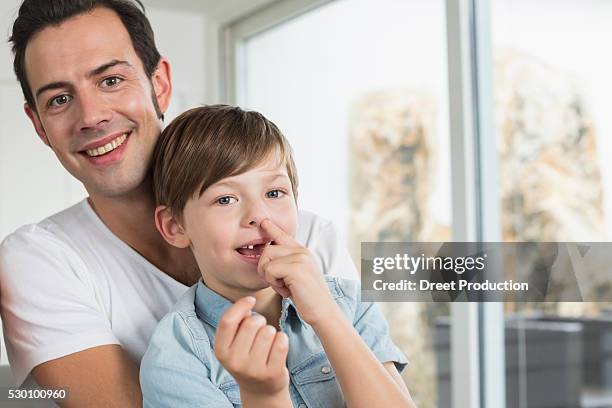 smiling father with son picking nose - picarse la nariz fotografías e imágenes de stock