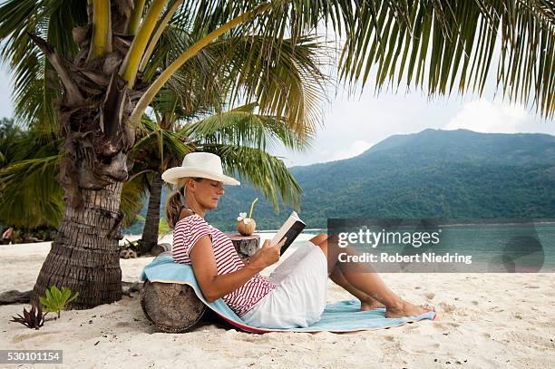 woman reading a book on the beach, koh lipe, thailand - women tanning beach drink stock-fotos und bilder