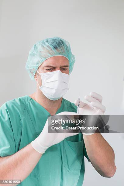 surgeon in hospital, holding syringe - surgeon holding needle stock-fotos und bilder