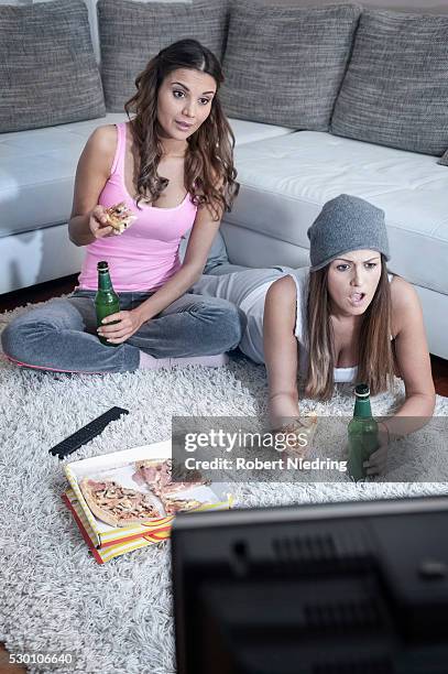 two female friends side by side on carpet at home watching television - faze rug stock pictures, royalty-free photos & images