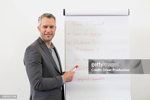 businessman at speaker desk with flip chart in auditorium - flip the script stock pictures, royalty-free photos & images