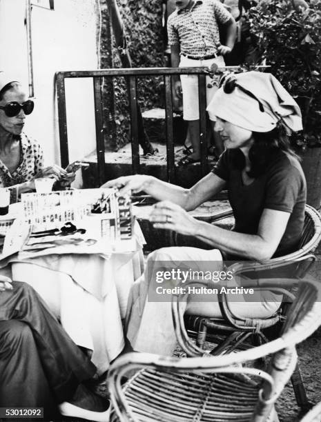 Jacqueline Kennedy Onassis , the wife of Greek shipping magnate Aristotle Onassis and former US first lady, reaches for the Italian magazine 'Genti,'...