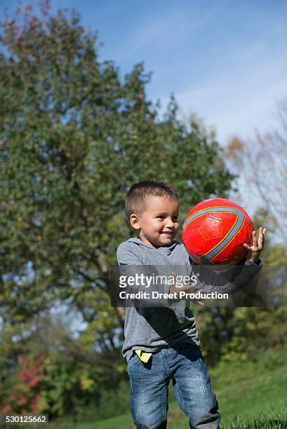 young boy catching red football happy - dreiviertelansicht foto e immagini stock