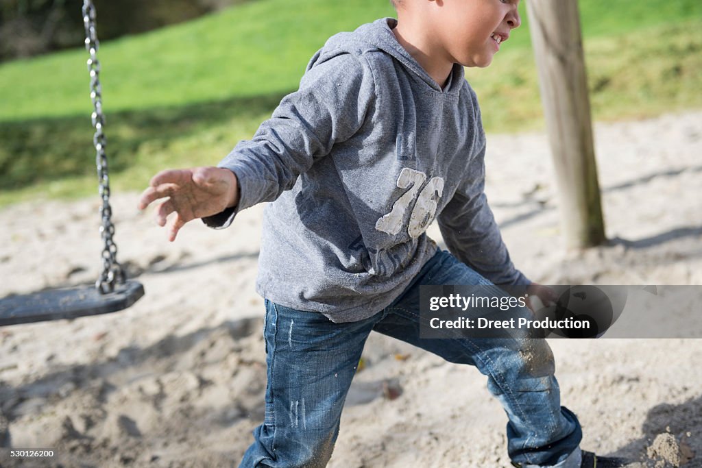 Boy playing swing playground sand action