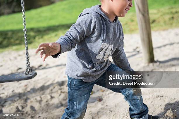 boy playing swing playground sand action - swing tag stock pictures, royalty-free photos & images