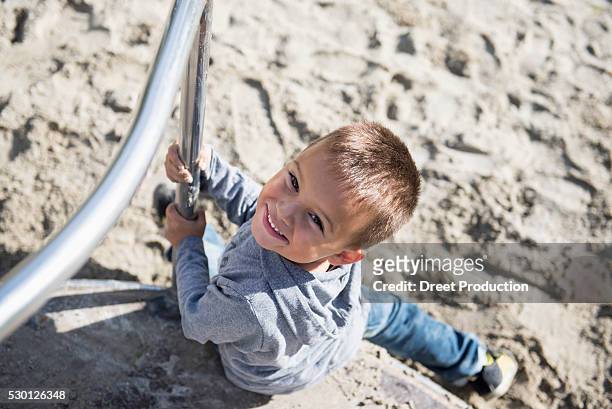 playground carousel small boy sitting smiling - draufsicht stockfoto's en -beelden