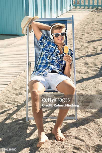 male teenager beach sunglasses listening music - deckchair stock pictures, royalty-free photos & images