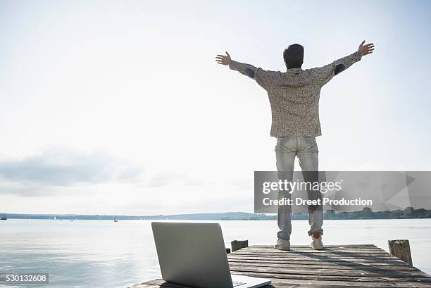 man lake happy laptop computer jetty - voetgangersbrug stockfoto's en -beelden