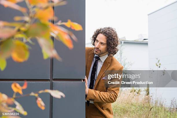 man suit watching suspicious nosy wall hiding - suspicion stock pictures, royalty-free photos & images
