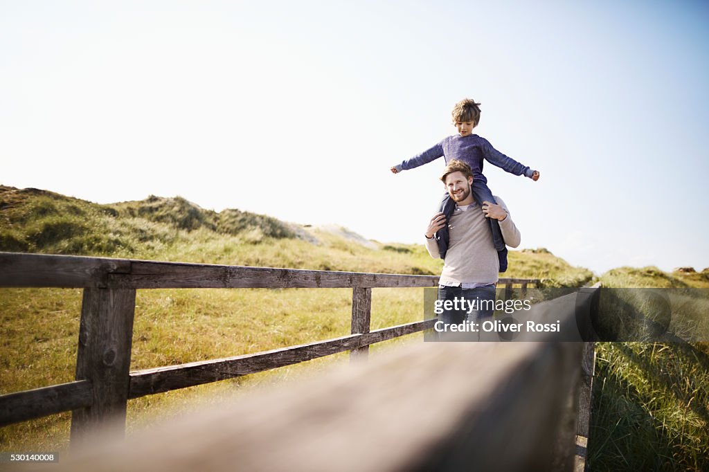 Father carrying son on shoulders at the coast