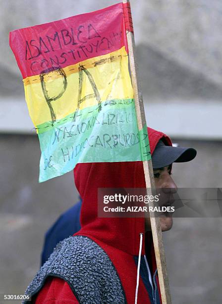 Un manifestante lleva una bandera boliviana con inscripciones relativas a una Asamblea Constituyente y la nacionalizacion de los hidrocarburos...