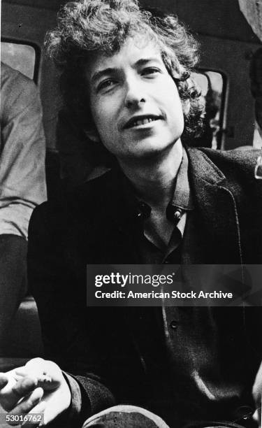 Portrait of American folk musician and songwriter Bob Dylan smiling and holding a cigarette, early 1960s.