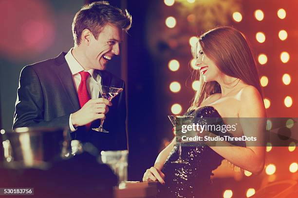 couple enjoying coctails in luxury bar - formele kleding stockfoto's en -beelden