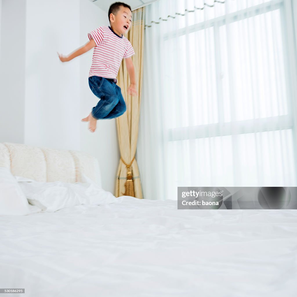 Asian boy jumping on the bed