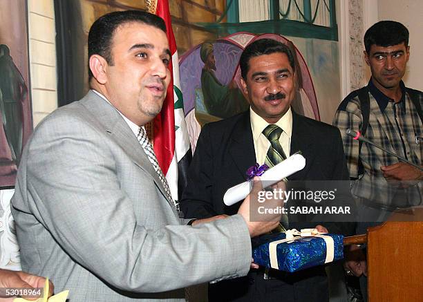 Dr. Mohammed al-Rubaye , president of the council of the Karrada district of Baghdad, presents a gift to Iraqi Major General Abu al-Waleed, the head...