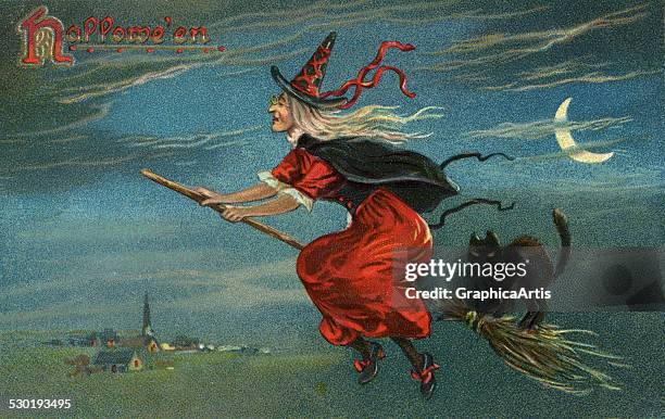 Vintage illustration of a Halloween witch and black cat on a broom, flying over a small town at night , 1908.