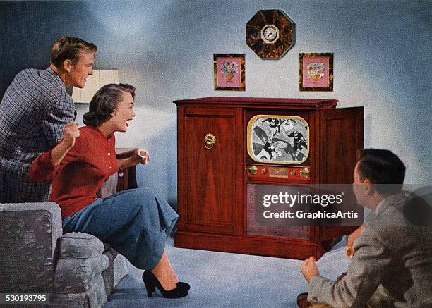 Couple and their son rooting for their favorite football team on television , 1953.