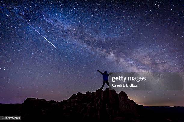 mann mit hellen sternschnuppe unter milchstraße galaxy - comet stock-fotos und bilder