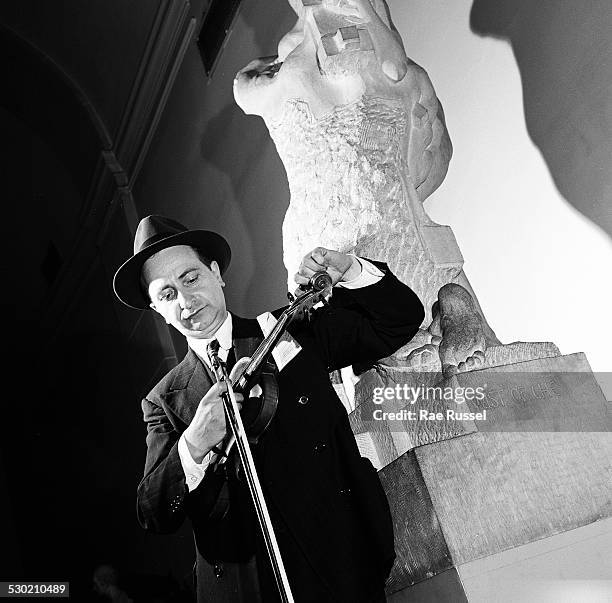 View of a violinist tuning his violin for a concert sponsored by WNYC radio and held at the Brooklyn Museum, Brooklyn, New York, New York, 1947.