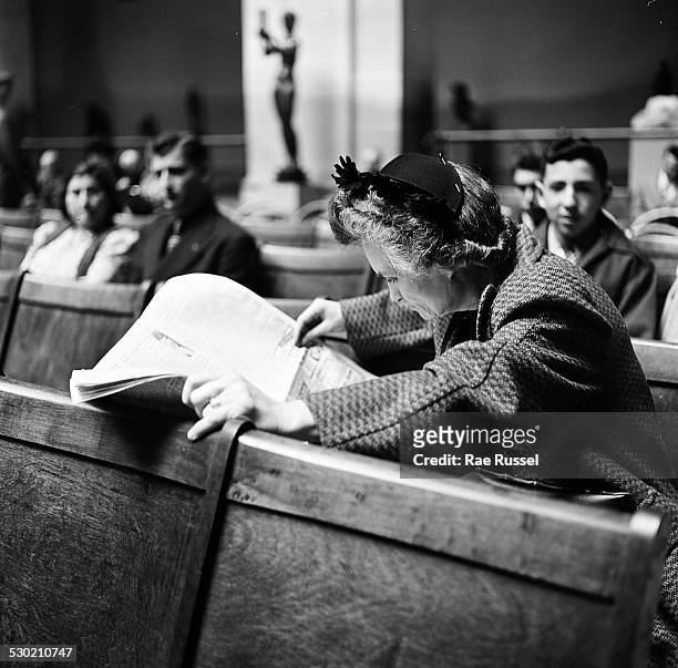 View of the crowd watching a concert sponsored by WNYC radio and held at the Brooklyn Museum, Brooklyn, New York, New York, 1947. A woman reads the...
