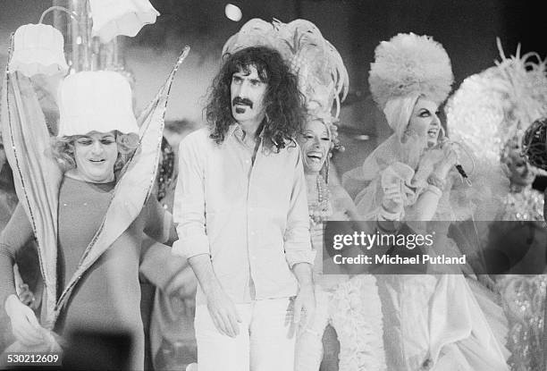 American musician, singer-songwriter and composer Frank Zappa on stage with showgirls, Paris, 29th September 1974.