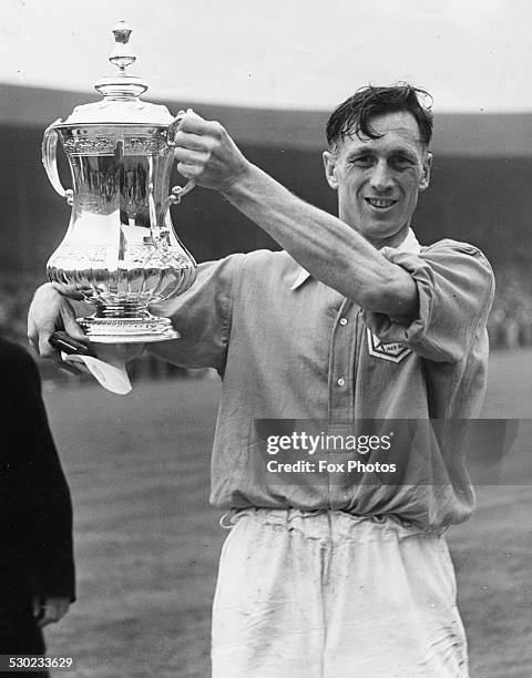 Portrait of Arsenal Football Club captain Joe Mercer, smiling as he holds up the FA Cup following the teams win, April 29th 1950.