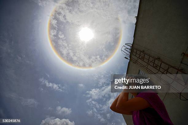 Woman looks at a halo in Caracas on May 10, 2016. The halo is an optical phenomenon produced when light interacts with ice crystals suspended in the...