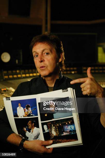 Paul McCartney points to a picture of himself in a souvenir photo book of the 1985 Live Aid charity concert, Air Studios, London 24th November 2004....