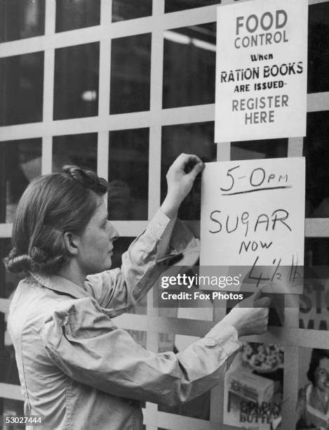 London shopkeeper puts up a sign announcing the new price of sugar as revealed in the Budget, 27th September 1939. The price has risen by a penny a...