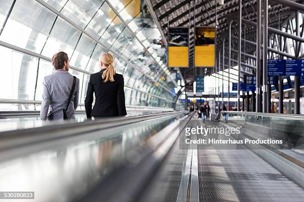 business travellers on man conveyor at airport - travolator stock-fotos und bilder